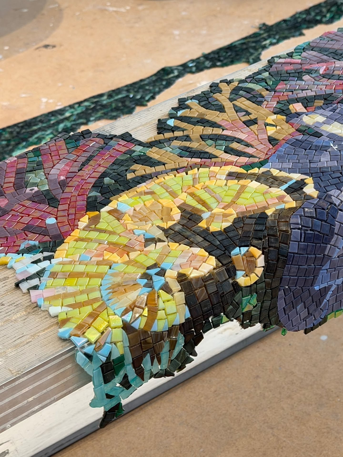 Mosaic panels being assembled by hand in the studio — coral and sea life emerging piece by piece